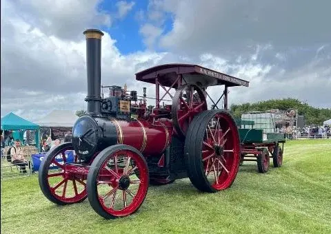 A preserved maroon steam traction engine with trailer on display among the show crowds