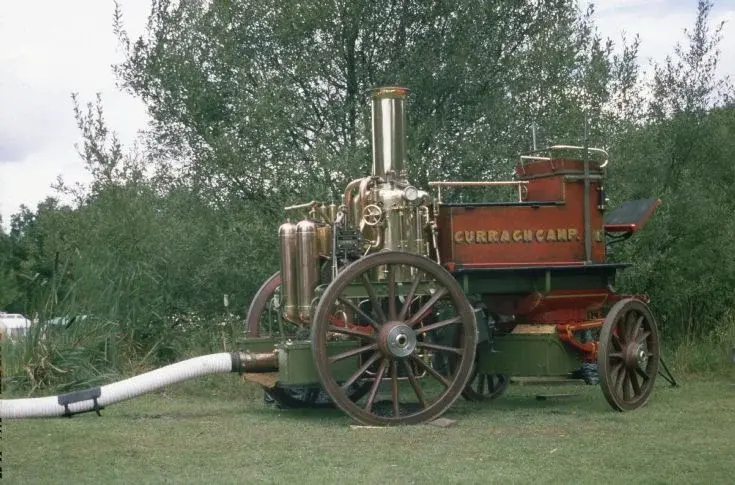 A restored brass and red steam-powered fire pump on display at the show